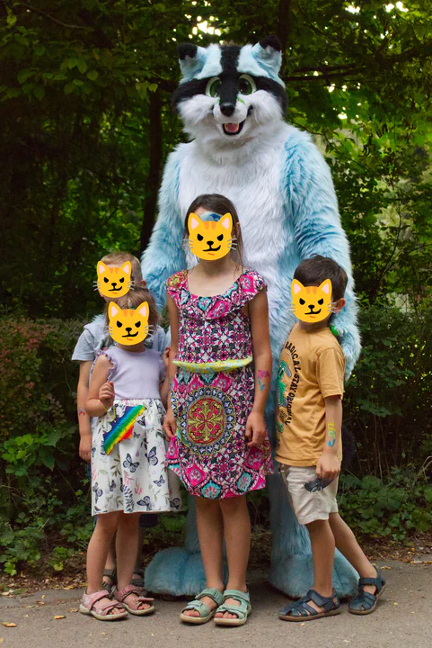 A blue racooon fursuiter posing for a group picture with four children